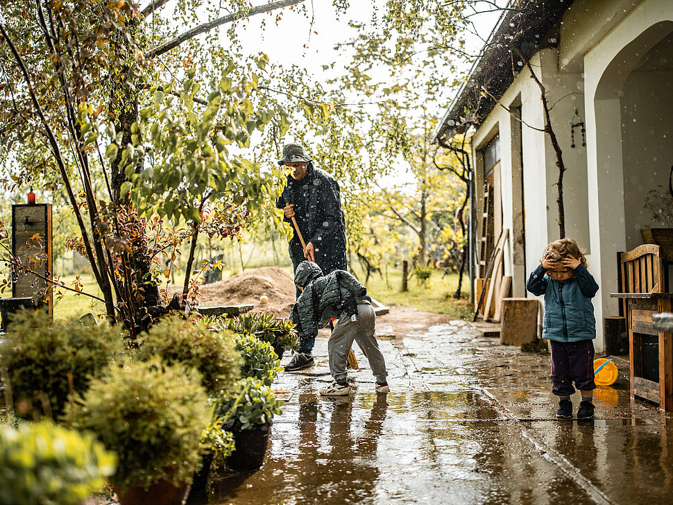 Vater und Söhne wischen von Regenwasser überflutete Terrasse
