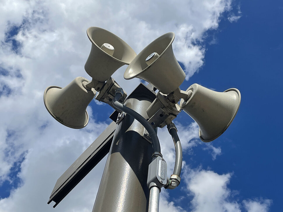 Warnsirenen an einem Mast vor blauem Himmel