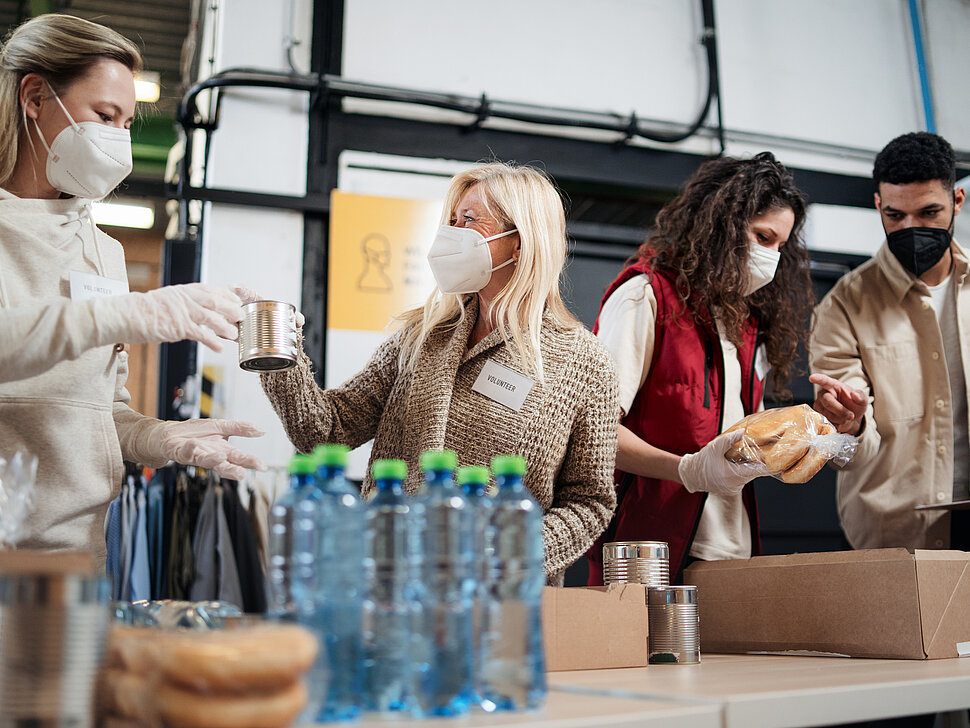 Menschen mit Gesichtsmaske verpacken Lebensmittel