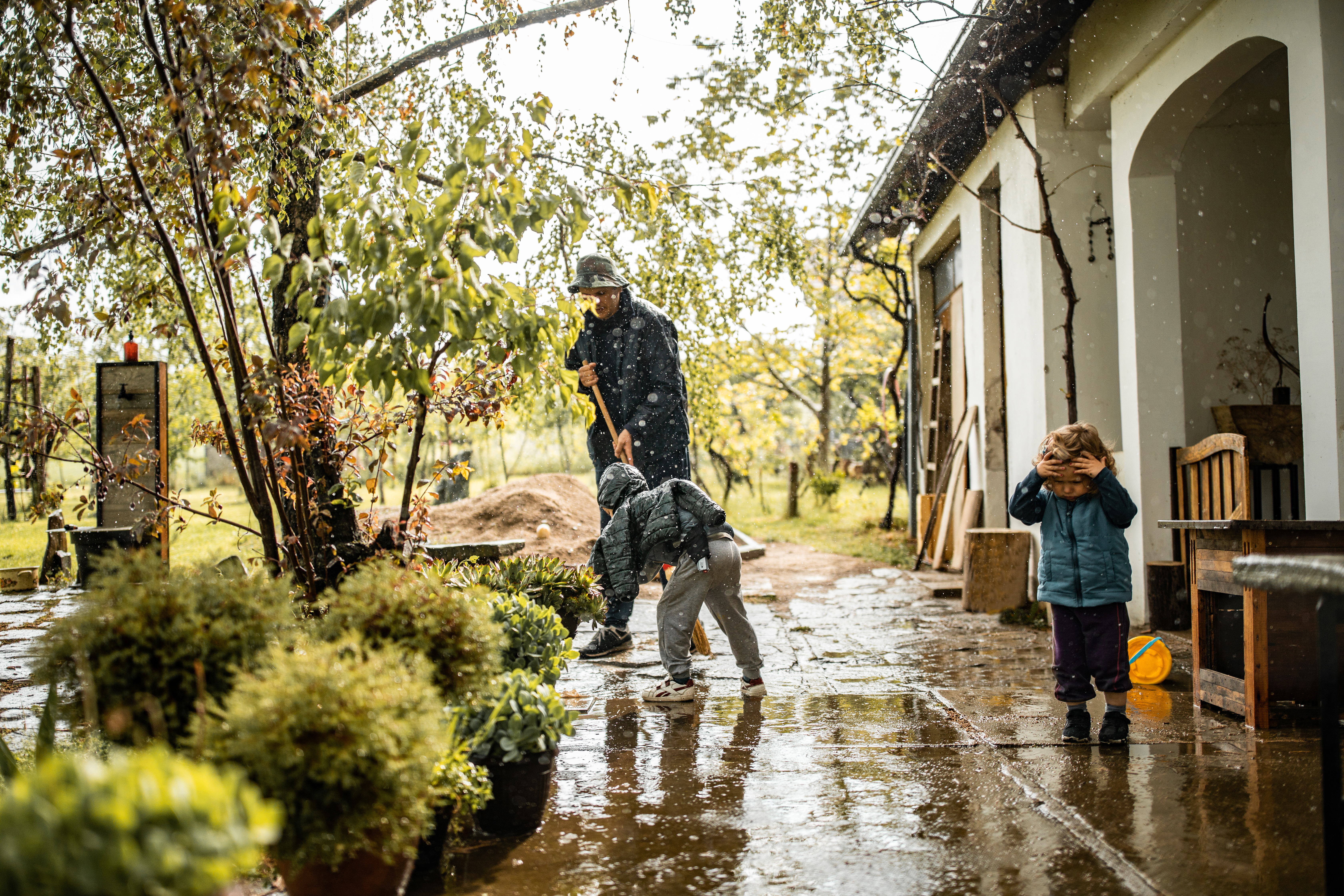 Vater und Söhne wischen von Regenwasser überflutete Terrasse