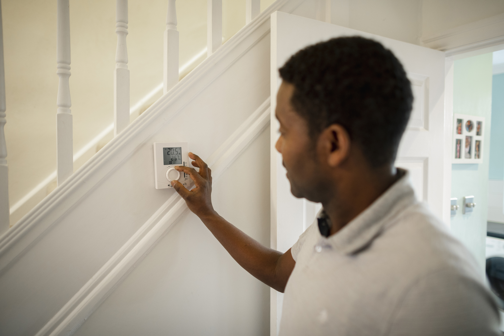 Menn dreht an einem Thermostat in seinem Haus