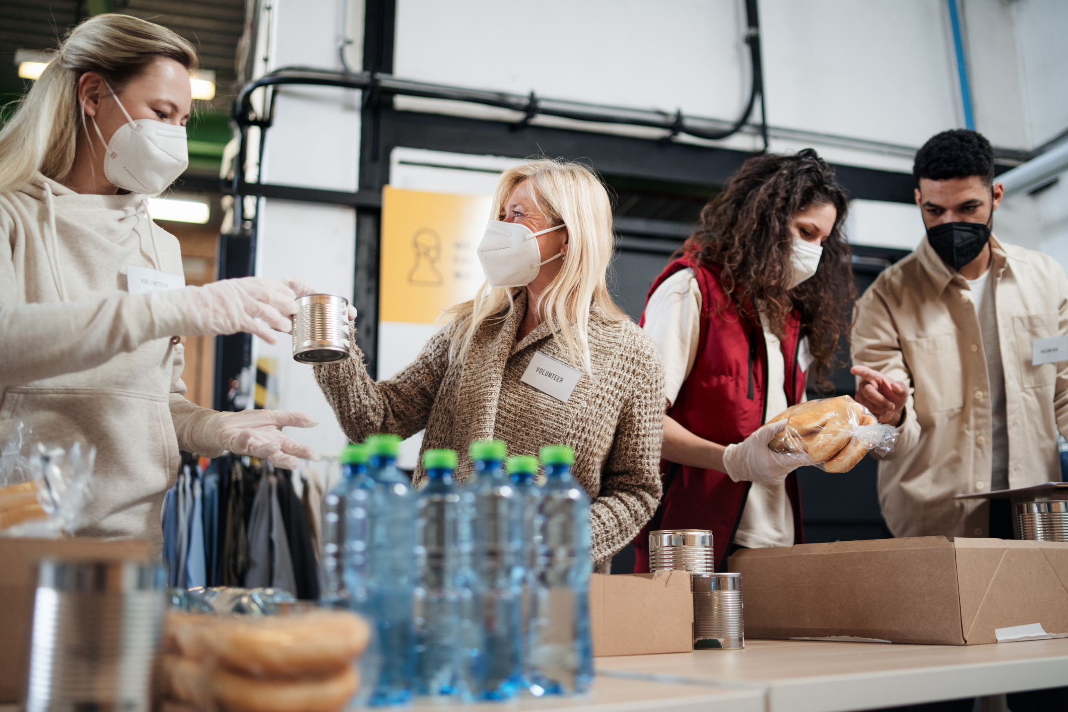 Menschen mit Gesichtsmaske verpacken Lebensmittel